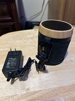 Photo showing House of Marley portable speaker alongside its power adapter on a wooden surface.