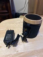 Photo shows House of Marley speaker with wooden top and fabric sides, power adapter, and audio cable on wooden surface.