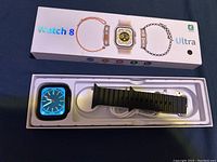 Photo of Watch 8 Ultra smart watch in original packaging with black strap and charger visible
