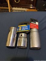 Photo of three metal socket tools, two 30mm and one 1 1/4 inch labeled OEM socket with packaging tag visible.
