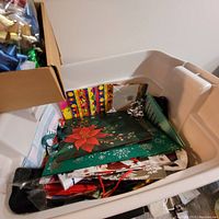 Top view of the medium plastic storage bin filled with many Christmas gift bags, showing colorful floral and holiday themed designs and one small box.