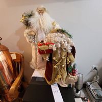 Two large Santa/Saint Nicholas figurines shown side by side, one in cream and one in burgundy.