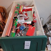 Photo of the storage bin filled with Christmas wrapping paper, gift bags, and gift bows.