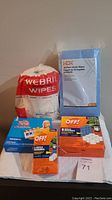 Photo showing a large pack of Webril wipes, a 40-pack of HDX Handy Wipes, a J-Cloth wipes package, and two boxes of OFF! bug repellent refills on a white cloth.