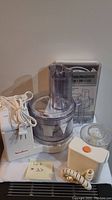 Moulinex food processor with clear processing bowl, power cord and front view showing logo.