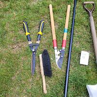 Six garden tools laid on grass for clear display.