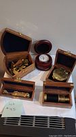 Full view of all four wooden boxes, each containing a different nautical navigation instrument, displayed on a table.