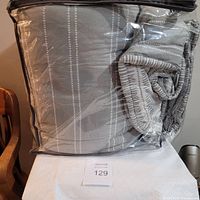 Comforter folded and packaged in clear plastic packaging on a table with white cloth underneath