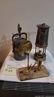 Three vintage brass coal mining lanterns and lamp stand on white cloth showing aged patina and condition