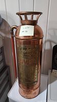 Front view of copper fire extinguisher with a note indicating lot number 10