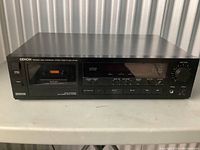 Front view of Denon DR-M20 stereo cassette tape deck showing entire unit on a table.