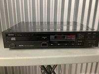 Front view of Denon CD player showing the full face with display, buttons and disc tray.