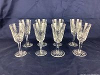 Eight Waterford crystal stemware glasses on dark cloth background, arranged in two rows.
