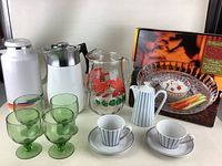 White vintage coffee pots, clear floral pitcher, green goblets, striped cups and saucers, and boxed Crystal Clear tortilla and salsa serving dish
