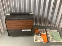Front and side view of the Bell & Howell Autoload movie projector showing its wood panel front and Bell & Howell branding.