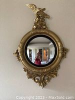 Full view of the Americana-style mirror showing the round reflective glass and gold eagle-topped frame.