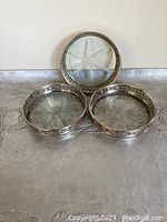 Three sterling silver rimmed glass coasters showing floral embossing and glass star pattern.