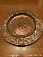 Copper plate with floral and ornamental border design, central embossed floral motif, visible signs of tarnish