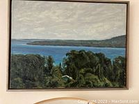 Framed painting of the Gatineau River landscape showing water, trees, and a cloudy sky.