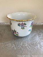 Front view of hand-painted Hungarian ceramic vase or bowl showing floral and butterfly designs, gold scalloped rim, and woven texture on the exterior
