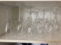 Photo showing multiple clear stemmed wine glasses arranged upside down on a shelf, displaying different bowl sizes and stem heights.