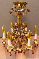 Full view of chandelier showing six arms with bobeches, faux flame bulbs and amber glass drops