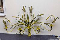 Front view of the yellow Italian 1950s metal floral 5-candle sconce showing overall design and five candle holders.
