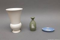 All three Wedgwood pieces: tall white vase, green jasperware vase, blue jasperware dish on neutral background