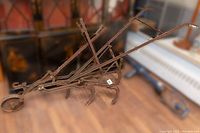 Side angled view of antique walk-behind cast iron cultivator plow showing tines, wheel, and handle assembly.