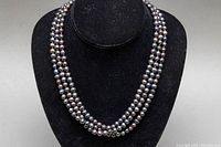 Front view of the 3-strand dyed baroque pearl choker showing lustrous pearls on black display.