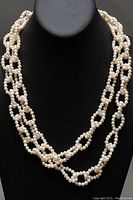 Long beaded pearl lariat necklace displayed on black jewelry bust showing chainlink loops and pearl texture.