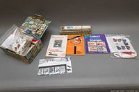 Overall view of box filled with assorted stamps, catalogs, and accessories spread on a table