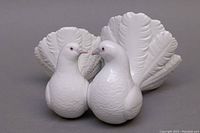 Front view of the two white porcelain doves with fanned tails shown facing each other.