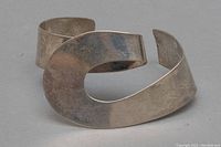 Front view of open-ended modernist cuff showing abstract curved design