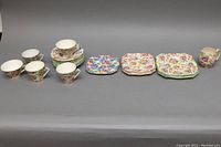 Wide shot showing entire set lined up with cups, plates, saucers, and creamer, all with floral pattern.