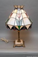 Full view of vintage table lamp with stained glass shade showing bulb and cord.