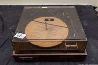 View of Westinghouse turntable with plastic dust cover closed, showing wooden base and record platter with paper instructions.