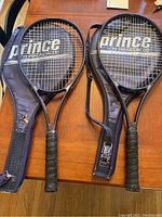 Two Prince CTS 110 tennis racquets in black with cases showing wear and cracking on cases and grips.