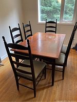 Wide angled shot of dining table with 6 chairs surrounding it in a room with wooden floor and window.
