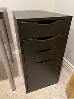 Filing cabinet front showing three drawers with integrated hand pulls and dark finish