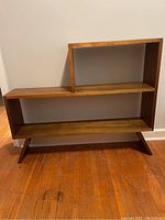 Front view showing asymmetrical two-tier shelf design and overall finish