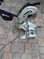 Full view of Mastercraft 10 inch mitre saw with dust collection bag attached, black handle, silver body.