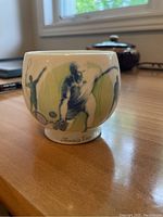 Side view of the ceramic cup showing illustrations of tennis players and the words 'Tennis Cup' near the base.