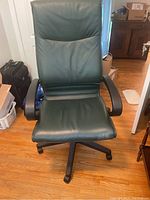 Front view of the dark green vinyl high-back office chair showing padded seat and backrest with black armrests and five-legged caster base.