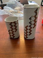 Photo front view of a pair of Zenit Royal Copenhagen vases on wooden surface showing their geometric copper pattern