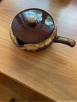 Top and side view of vintage Roseville bean pot with handle and lid, showing glaze details and chip on inside lid edge