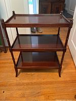 Front view of the antique wooden shelf showing three shelves and turned wooden posts.