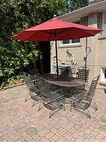 Full view of table, six chairs, umbrella and base on paved patio