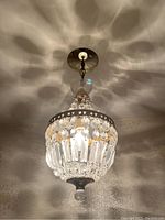 Overall view of unlit ceiling fixture showing crystal prisms and metal frame.