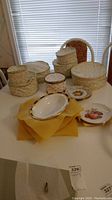 Overview of multiple floral-patterned fabric storage bags and a selection of loose plates including an oval platter and round fruit motif plate.